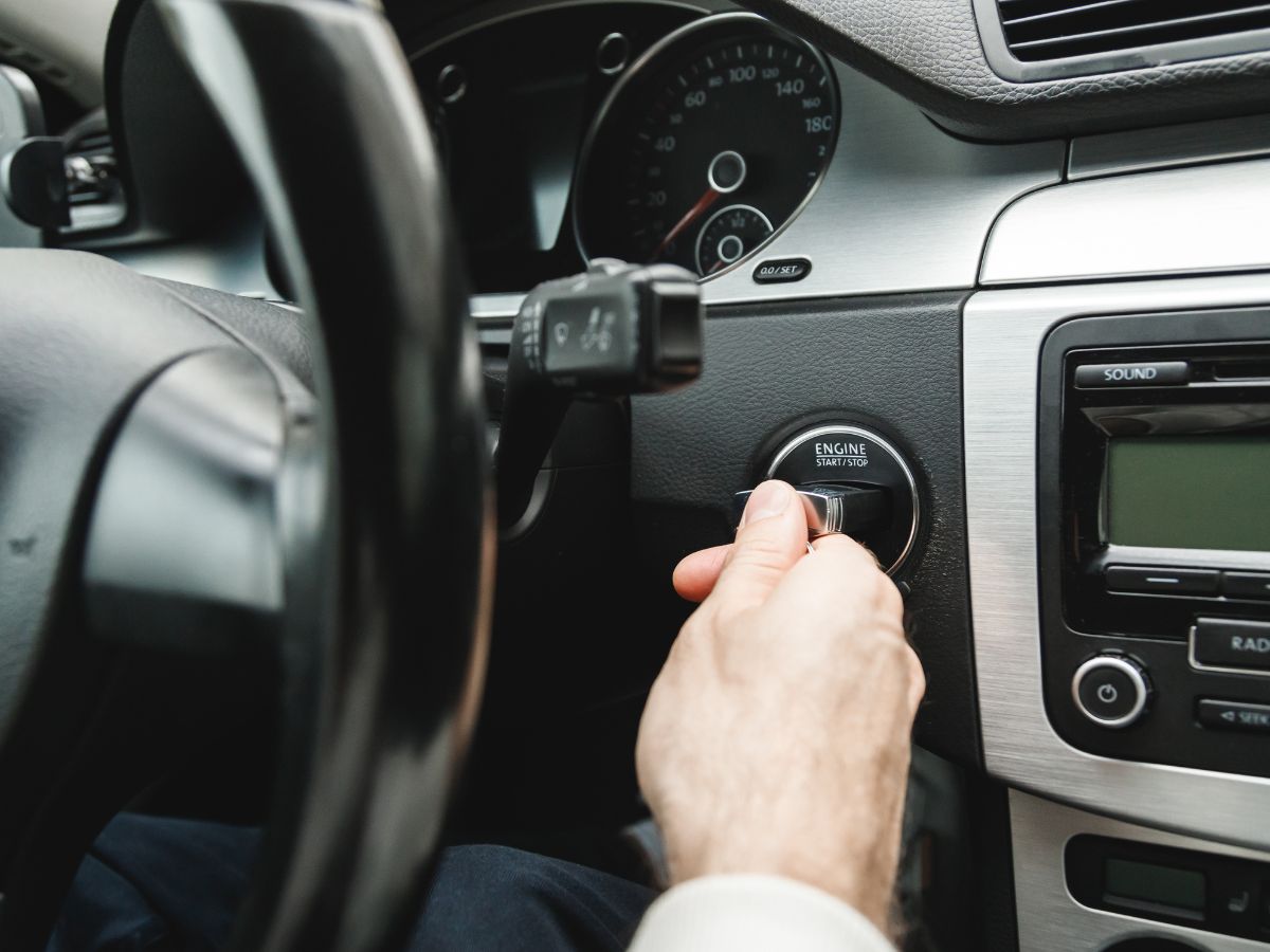 person using a push to start button in their car