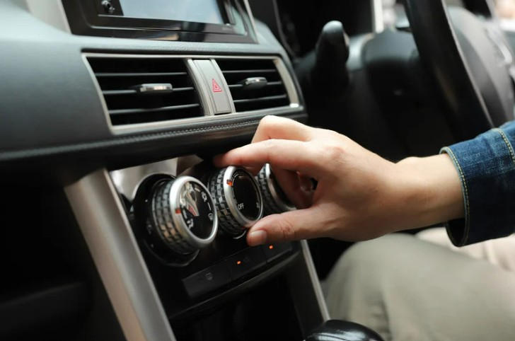 Hand adjusting the air conditioning in a car